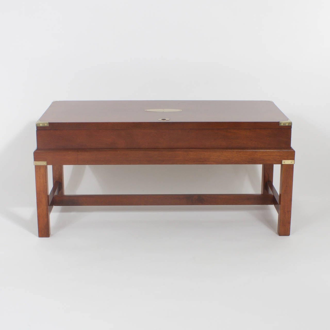 Campaign gun case mounted as a coffee or cocktail table twith storage in a presentation display box on top. Featuring sleek no nonsense Mid Century type form and the warm color of mahogany. Campaign style hardware and a blank plaque on the top that