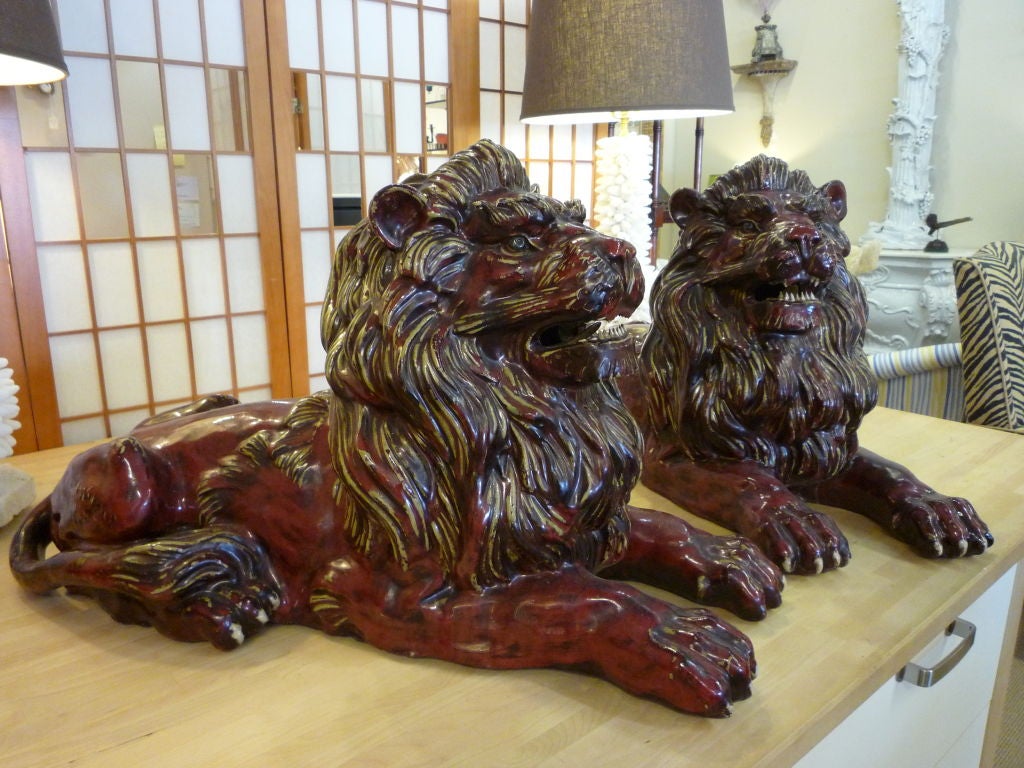A pair of hand formed stoneware lions, with great detail. The glaze has been applied in a way to accentuate the drama of the mane, face and tail.


