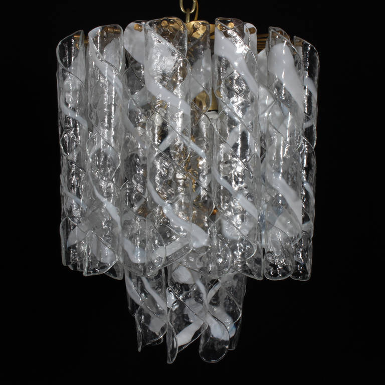 A two-tiered Mazzega Italian midcentury Murano glass chandelier. White to clear twisted glass sheathes over a solid brass frame hung from a thick brass chain. Highest quality 1970s lighting. The new classic. Newly wired and polished.