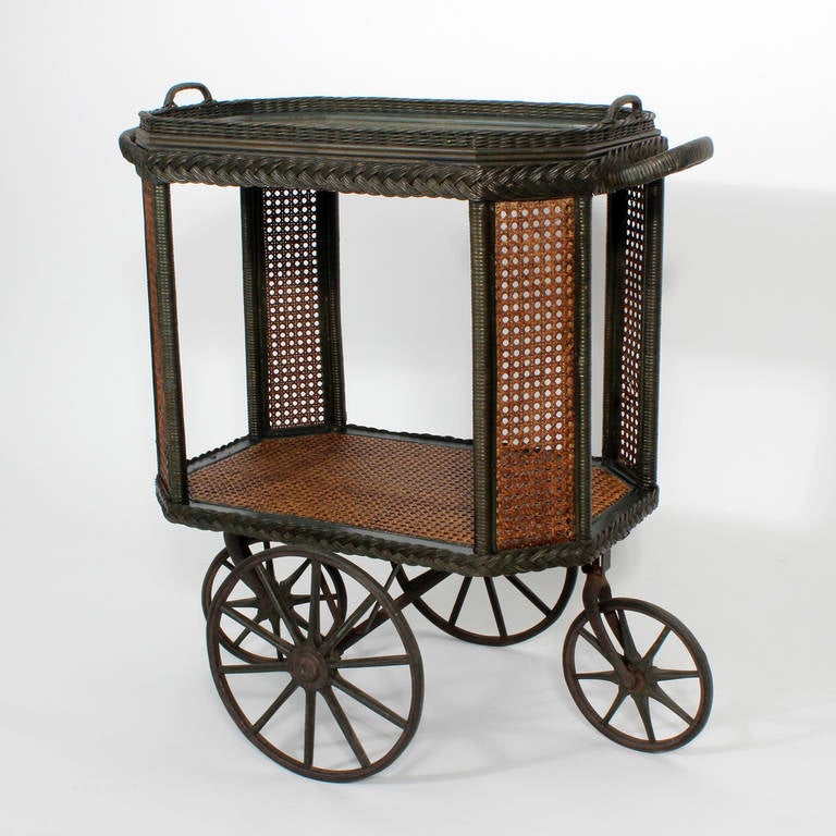An early 20th century wicker drinks or tea cart on industrial wheels with removable serving tray. Passed down from a time when gracious living was an art form, this cart, is in almost impossible great condition.  Probably Haywood Wakefield.