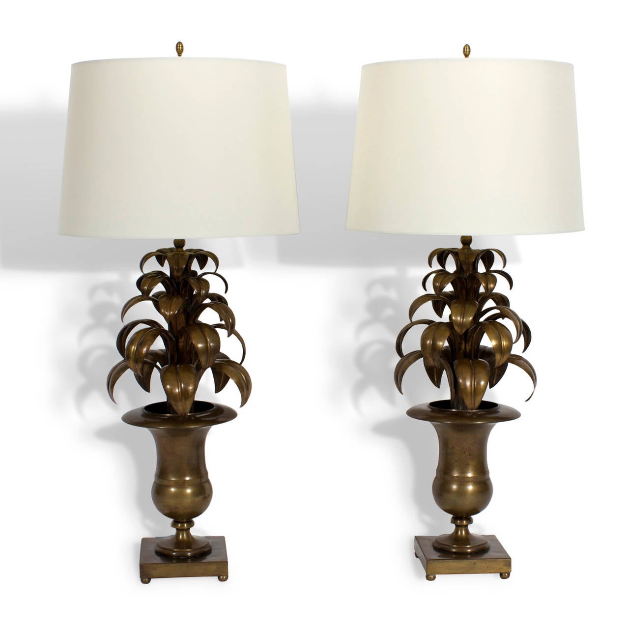 A pair of all brass Italian table lamps with layers of graceful leaves in campana shaped urns on square plinths with ball feet. Chic, modern with a warm patina. Never need water. Newly wired.

.