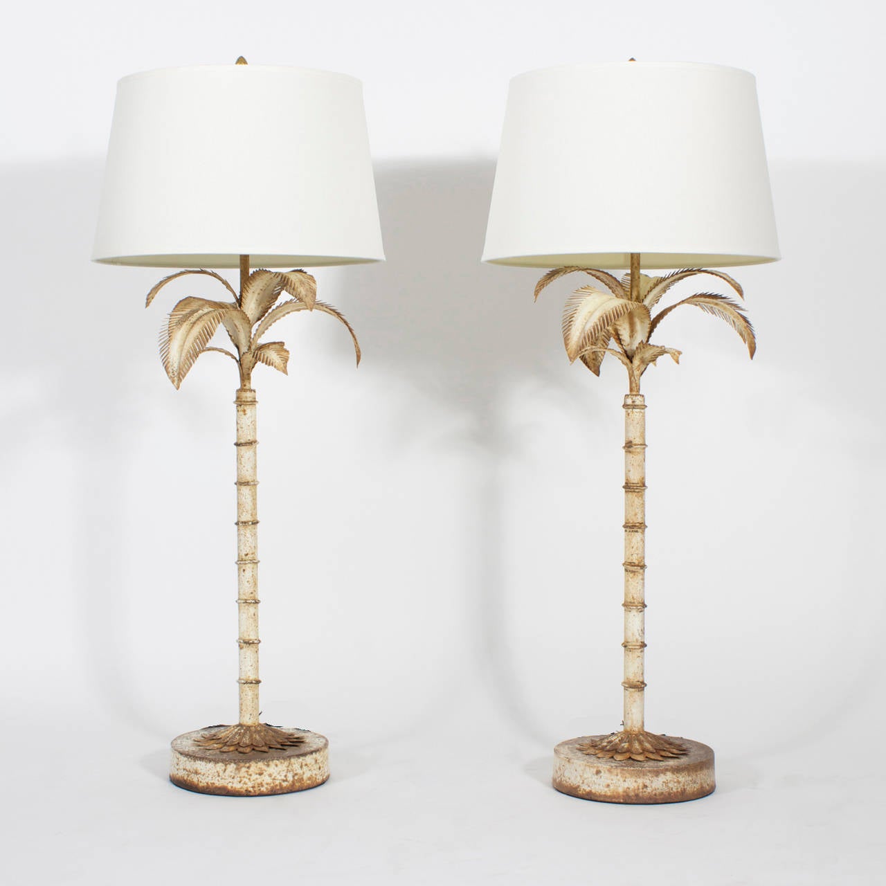 A pair of Italian tole palm tree table lamps with charming old world oxidation on white paint, discretely outlining the lamps. Classic form and bold scale. Only nature can create this alluring decorative look.

