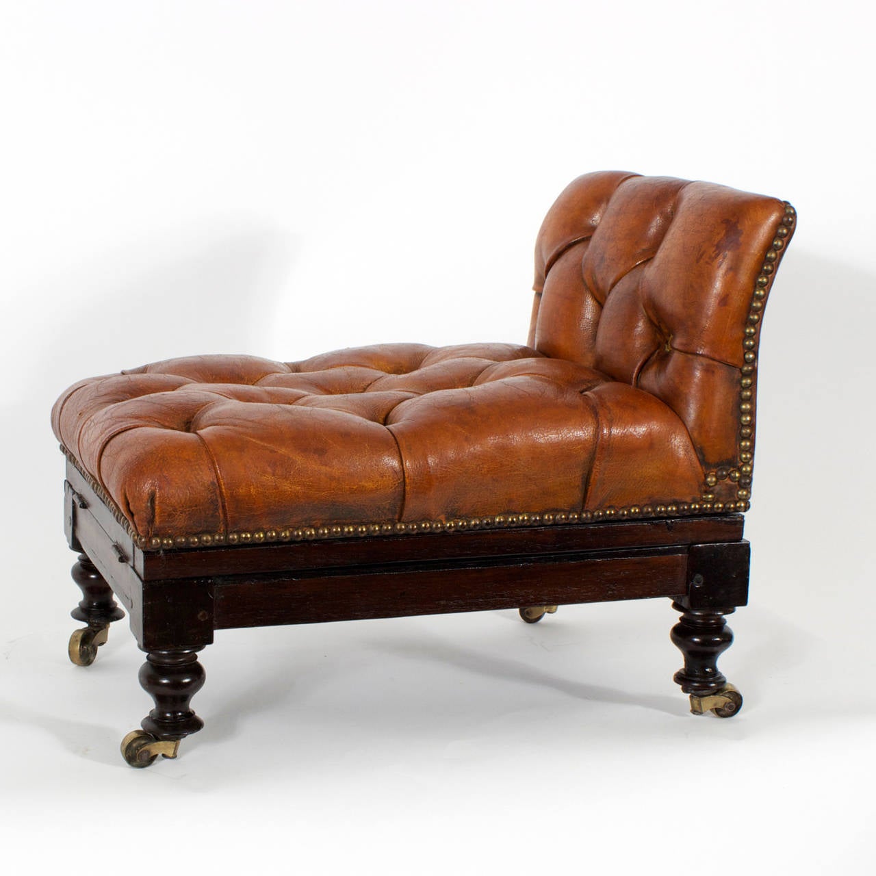 Here is a fine, 19th century, brown leather, button tufted foot stool with mahogany frame and brass tacks over turned legs and brass wheels. Having the added feature of adjustable angles, of raising 6