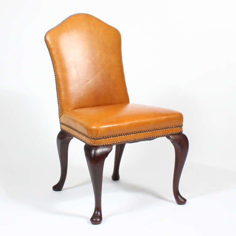 A set of 4 Georgian style leather chairs, with decorative brass tack accents, shaped tops and cabriole legs. These are a dynamite set, so decorative, they almost take your breath away.  Newly polished.
