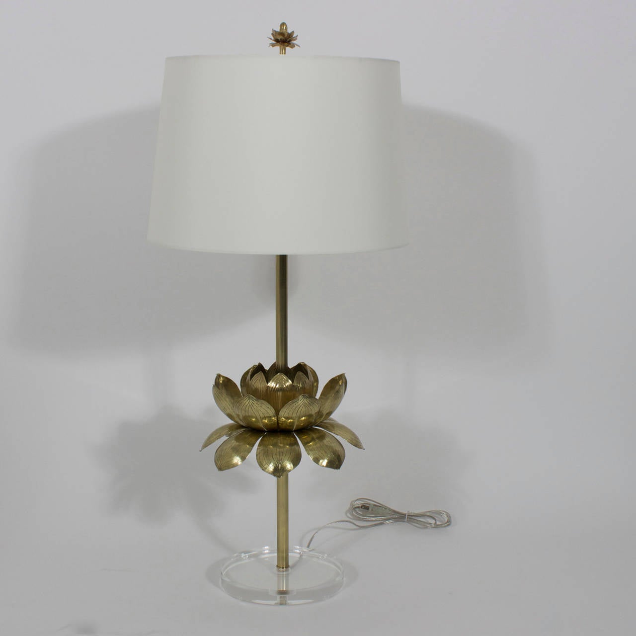 A pair of chic, custom-made table lamps with brass stems leading to etched brass lotus flowers, the vintage brass flowers probably by Feldman, all on round Lucite bases, topped with a custom lotus flower finial. Newly polished and wired.