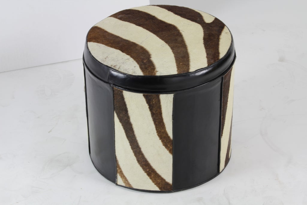 Here is a black leather and zebra patterned cow hide foot stool or hassock, with an upbeat vibe.