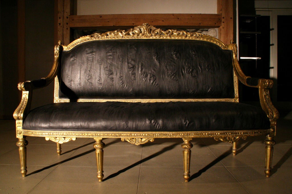 Pair of French Louis XVI hand carved gold gilded arm chairs, c. 1930s, France. Newly reupholstered in goth black puckered leather. Very comfortable and striking.<br />
<br />
Seat Measurements:<br />
17.5