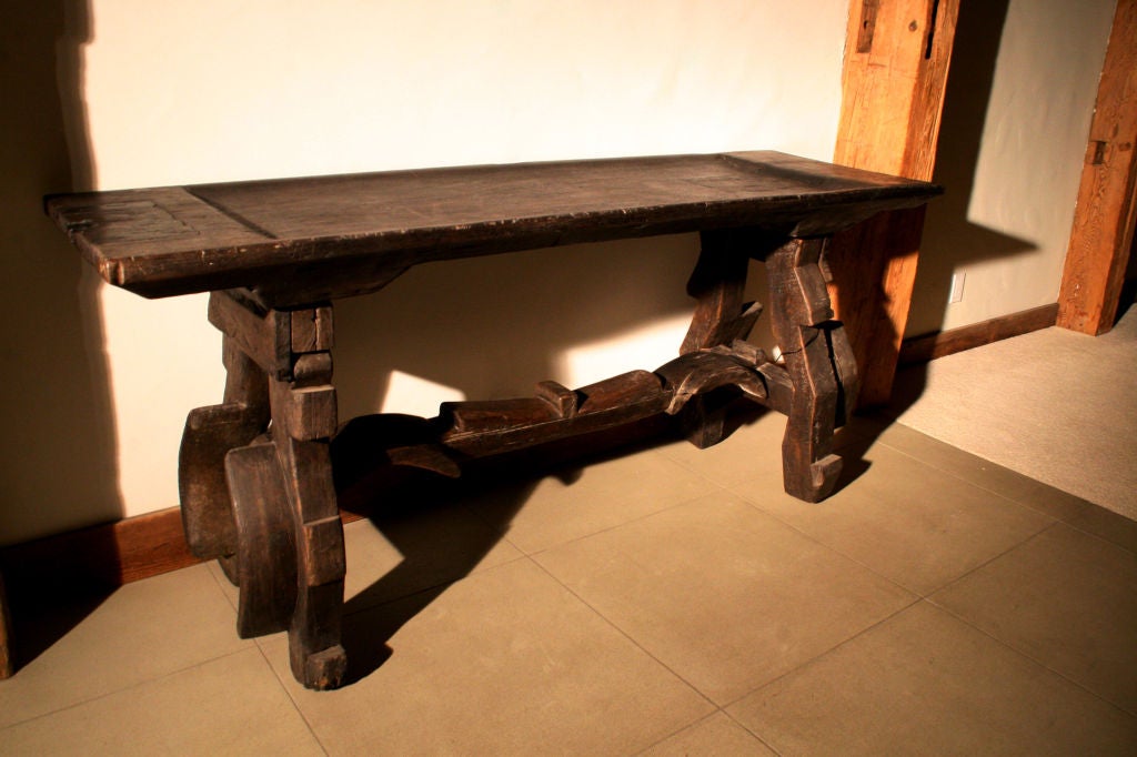 c. 1800's Spanish wooden ox yoke console table. Solid wood table top attached to the ox yoke legs and stretcher frame, with original dark finish. Very heavy and sturdy. Great piece to be used in a hall, along empty wall space, or as a sofa table.