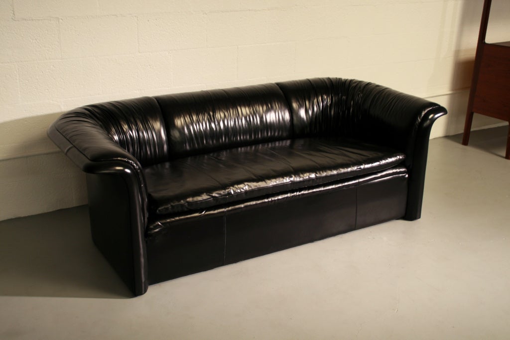 Pair of rare sexy black leather loveseats, designed by Dennis Christiansen for Dunbar c. 1970s, USA. Original leather with exquisite gathered leather details throughout back and arms, all continuous. Beautiful curved fanned back continuous through
