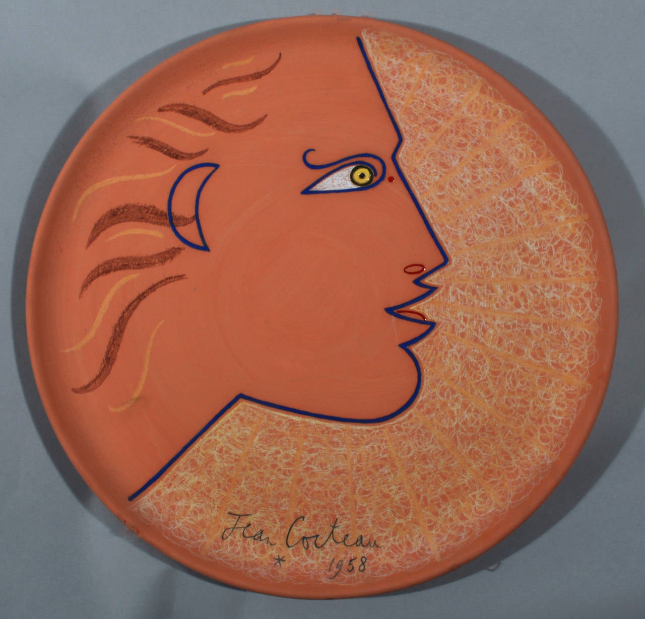 Phebus- Apollon. 
Signed and dated by Jean Cocteau, 1958. 
Number 11 of an edition of 30.

Painted and partially glazed terracotta dish.

Marks: Signed and dated on front; 
On reverse inscribed Edition Originale de Jean Cocteau, Atelier