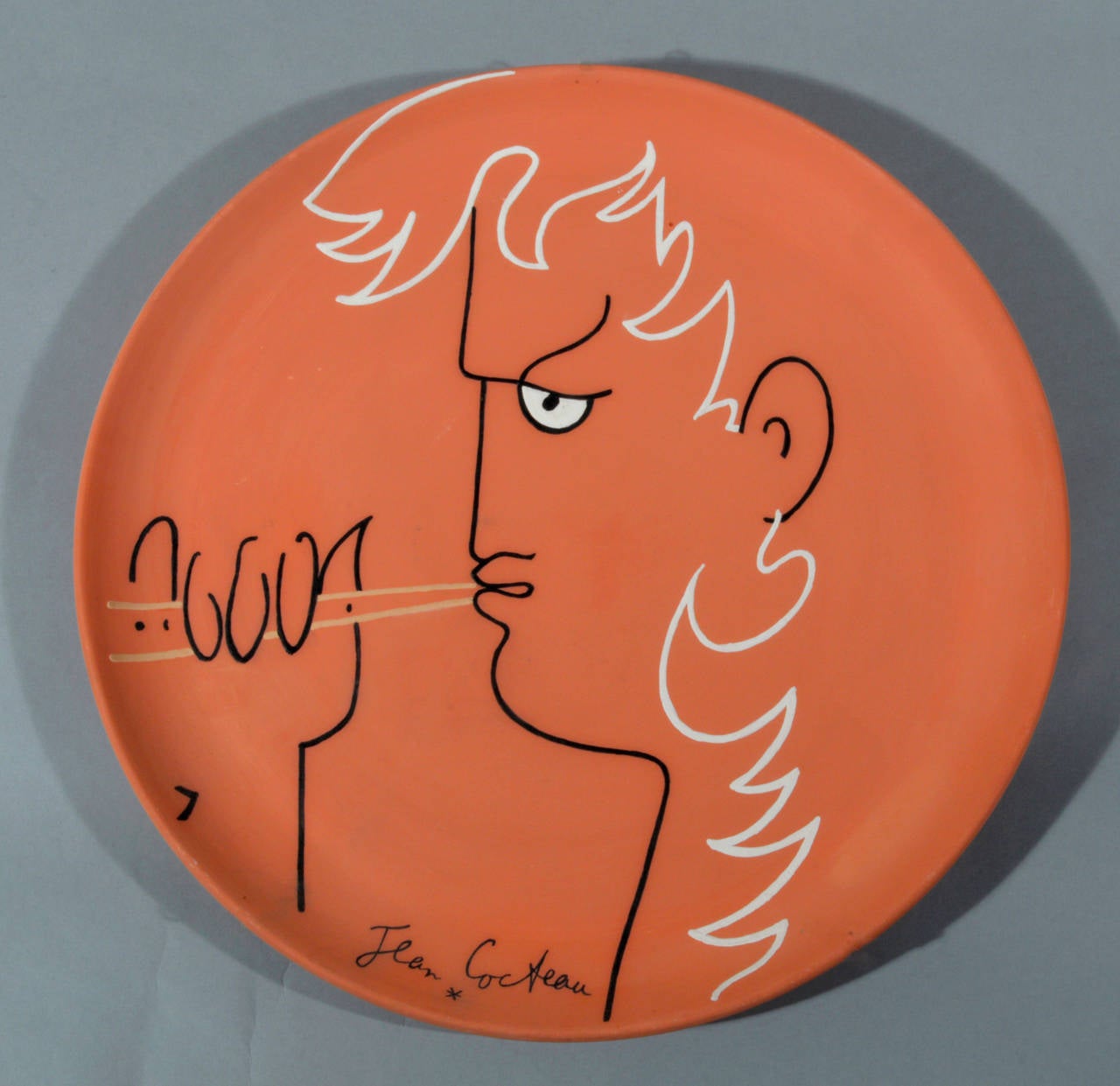 By Jean Cocteau (1889-1963).
Signed, dated 'Jean Cocteau, 1958' (lower center edge).

Painted and partially glazed terracotta dish.

Marks: Signed and dated on front;
On reverse inscribed Edition Originale de Jean Cocteau, Atelier