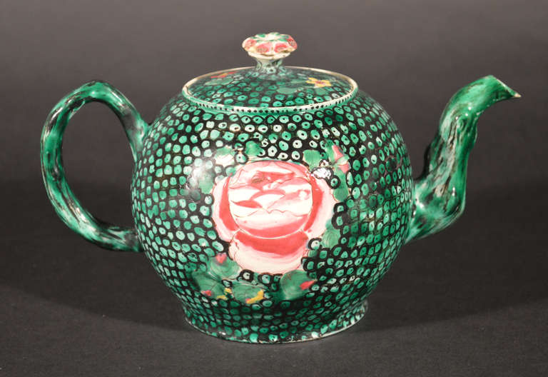 The Staffordshire saltglazed pot with crabstock spout and handles has a painted rose on a green shagreen green ground. The green ground is the rarest of the colours found on this type of teapot-blue and pink being much more common.

Reference: The