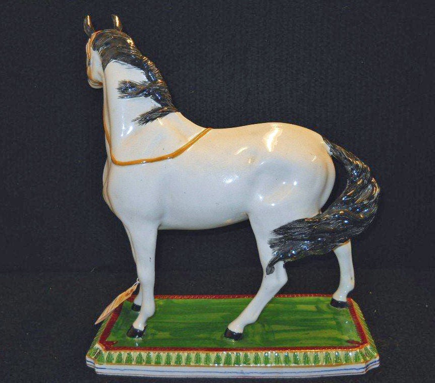 The Horse standing with its head to the right wearing a halter, the lead line lying across its back, on a canted rectangular base, the top green within a molded wreath border and glazed in claret, the sides molded with stiff-leaf tips similarly