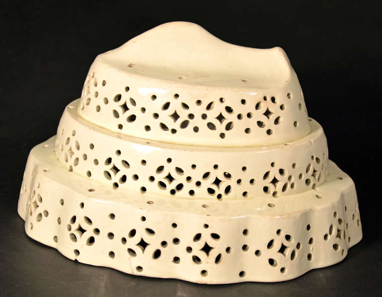 The plain creamware mold is probably Leeds. The mold is of triple stepped oval form with basal waved moldings each tier pierced with stylized roundels surmounted by a fish.

Pierced creamware mould such as this was for making moulded curds,