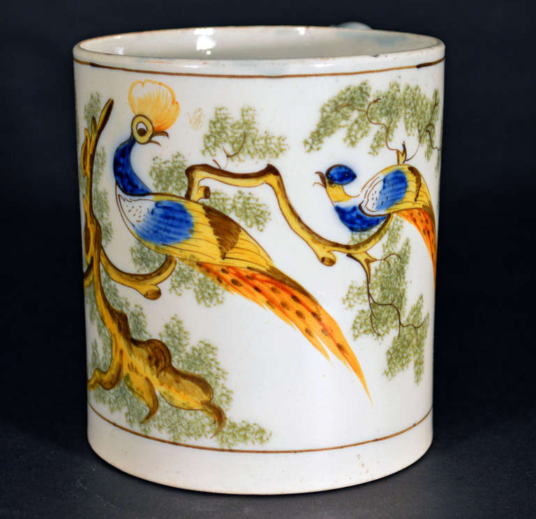 The pearlware peafowl tankard of cylindrical form has a wide double-grooved strap handle with an orange stripe. Two tiny pinholes have been created in the interior base probably as drain holes.

Reference: Illustrated Feathers and Foliage, George