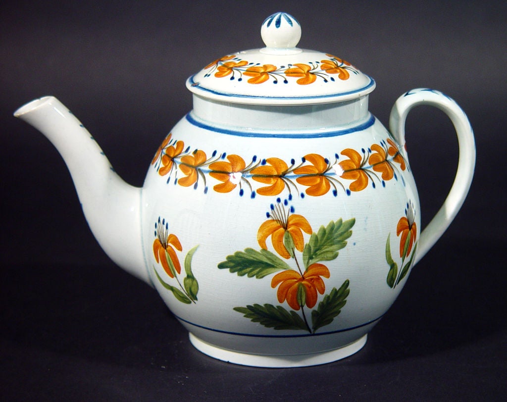 Charmante théière en poterie fraîche folky décorée de fleurs dans des tons orange et vert distincts dans un bon grand format.