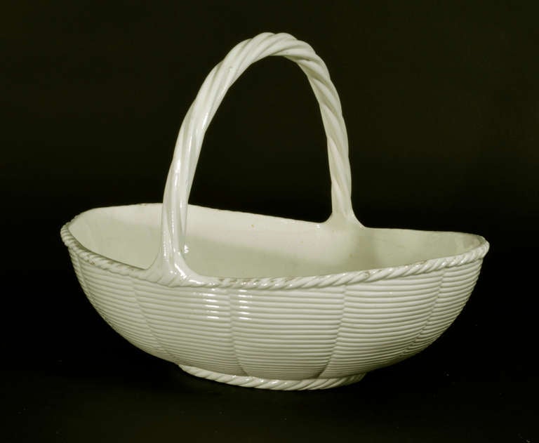 The oval basket has a wicker-type design with the top rim with a twist rope border.  The tall looped handle is of a twisted rope design.

Mark: Capital marked WEDGWOOD and capital R.