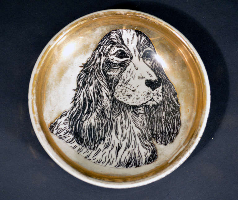 The deep circular dish is decorated with a cocker spaniel on a gold ground.  There is wear on the gold ground leading us to believe that this was used as dog bowl.

Reference: Fornasetti: The Complete Universe, Barnaba Fornasetti, Page 577, for