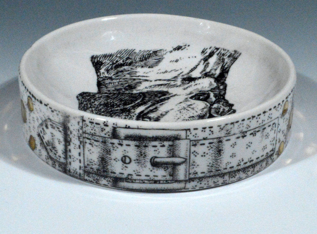 The Piero Fornasetti deep circular dish is decorated with a St. Bernard.  There is wear on the gold ground leading us to believe that this was actually used as adog bowl.

Reference: Fornasetti: The Complete Universe, Barnaba Fornasetti, Page 577,