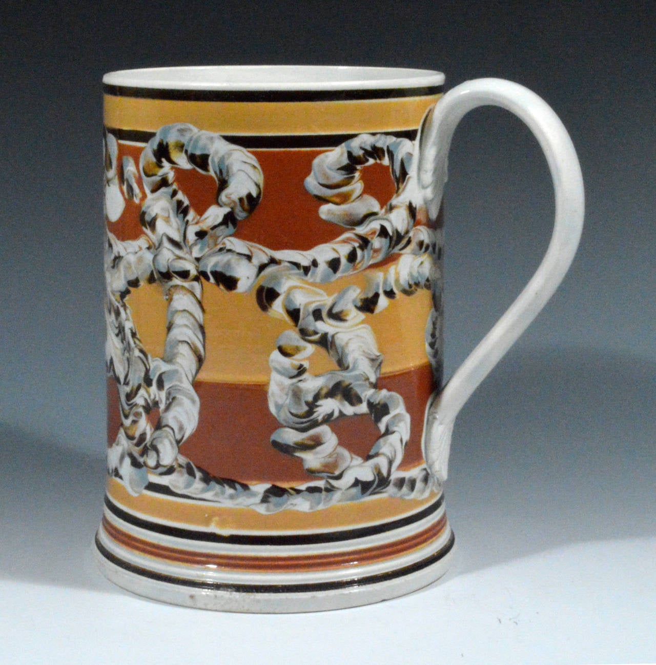 The large pearlware tankard with a n earthworm design over a series of bands of dipped ochre and red-brown.  the stepped foot decorated with similar bands.

