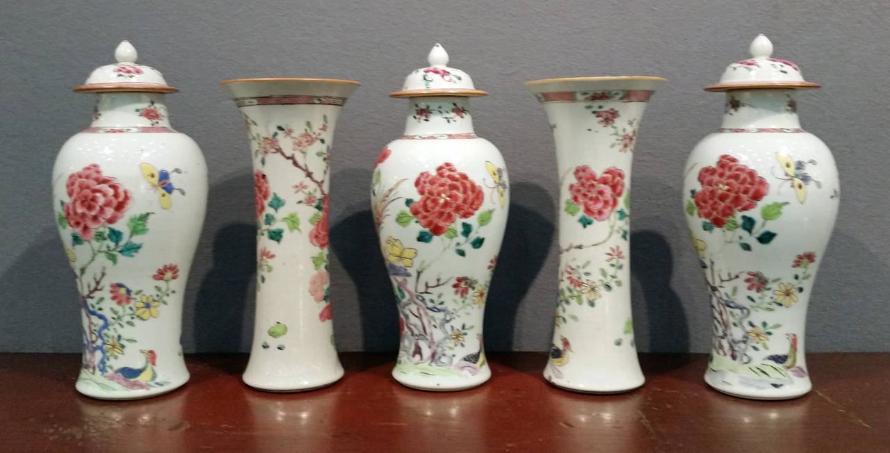 The vases three covered baluster and two trumpet vases are each painted in famille rose enamels with a well painted large pheasant on blue rockwork surrounded by exuberant famille rose flowering peony flowers and to each covered vase a large yellow