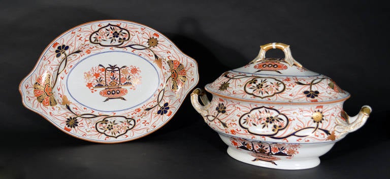 Spode new stone China ironstone tureen, cover and stand is decorated with an Imari pattern of a Chinese flower-basket filled to capacity with flowers and leaves in iron-red, gold and orange. The border with two quatrefoil cartouches alternating with
