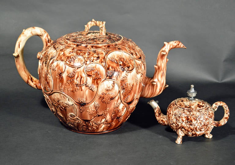 The massive Whieldon-type lead glazed punch pot and cover is of a heroic size.   The spherical is sponged in  manganese underglaze oxide and the body with well defined applied grape leaves and clusters of grapes. 
 
Reference: 

The Frank P. and