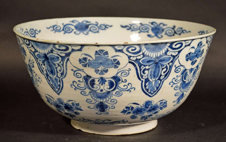 London or Bristol.

The bowl is fully decorated in blue and white with stylized flowers and geometrical motifs.  The interior with a large blue and white central floral composition with repeating stylized flower head and leaves on the upper