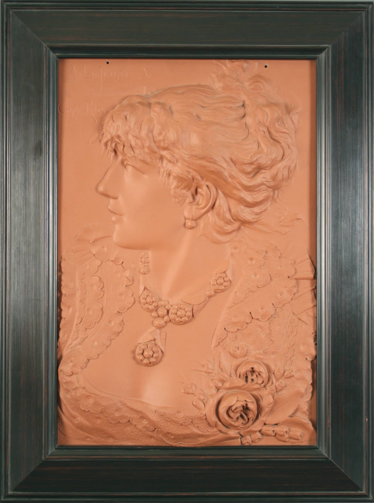 Uncommon American Art Nouveau period terra cotta wall plaque by Alphonse LeJeune, circa 1900, most likely the work of the Northwestern Terra Cotta Company of Chicago (1877-1956). The image is a stylish Victorian woman sculpted in high relief, quite