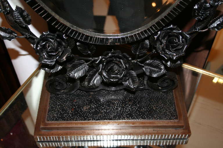 A French Art Deco period tabletop swivel mirror, beveled glass, circa 1930s. Silvered metal base, wrought iron rose theme frame painted black. In the style of Oscar Bach.