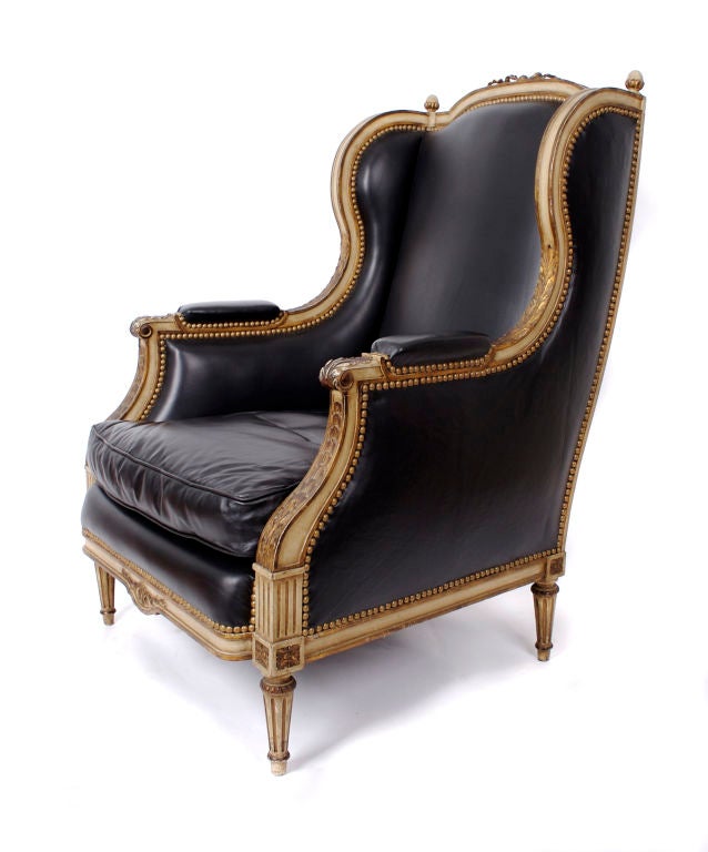 Pair of armchairs in the style of Maison Jansen. Black leather with antique white and gold trim; stud details.