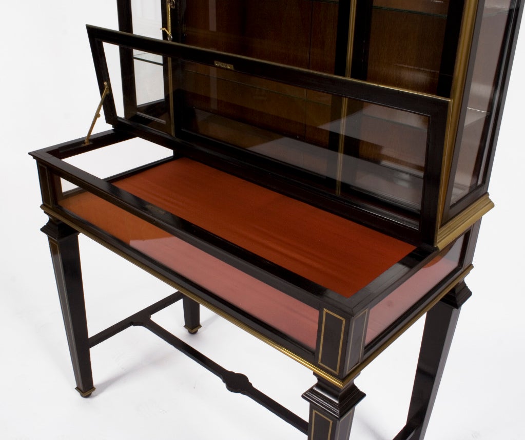 French neoclassical style display case in the manner of Maison Jansen, circa 1920s. Ebonized wood with brass trim and brass inlay.