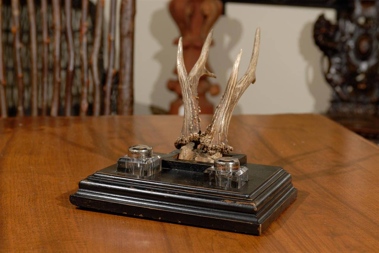 This handsome 20th Century desk set is fitted with double ink wells recessed on a black base, paired with antlers.  Possibly Hiessey Glass 'pots' with beveled rims, flip lids, and deeply incised 'star' pattern enhances the uniqueness of this piece.