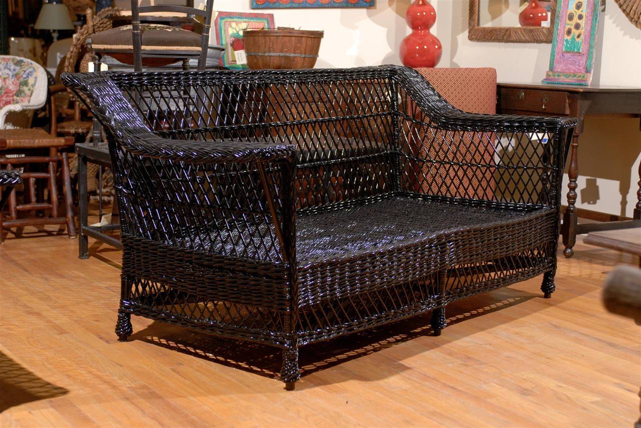 This is an American vintage wicker sofa, Circa 1920, painted black.  This sofa would fit in any casual situation, including sunrooms, screen porches, dens, or family rooms.