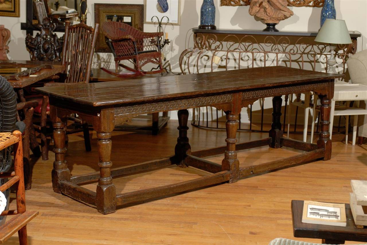This is a joined English oak refractory table with lots of lovely hand carvings along the apron. The legs are hand-turned and show beautiful wear and tear along the base.