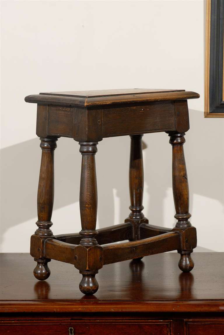 This small English joint stool dates circa 1910-1920s. The legs are joined by stretchers with bun feet.