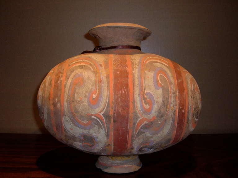 Very colorful Han dynasty Cocoon jar with cloud motif painted on terra cotta form.