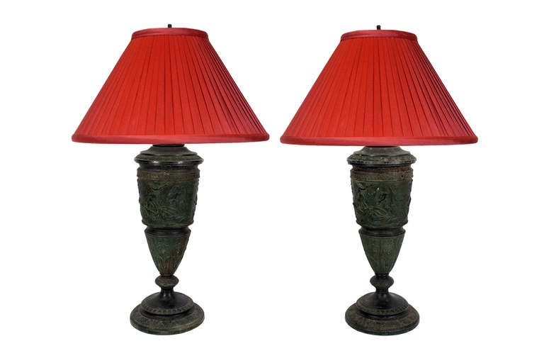 A pair of 19th century dark green patina Spelter vases mounted as lamps; featuring mythological scenes; with pleated red silk shades (24