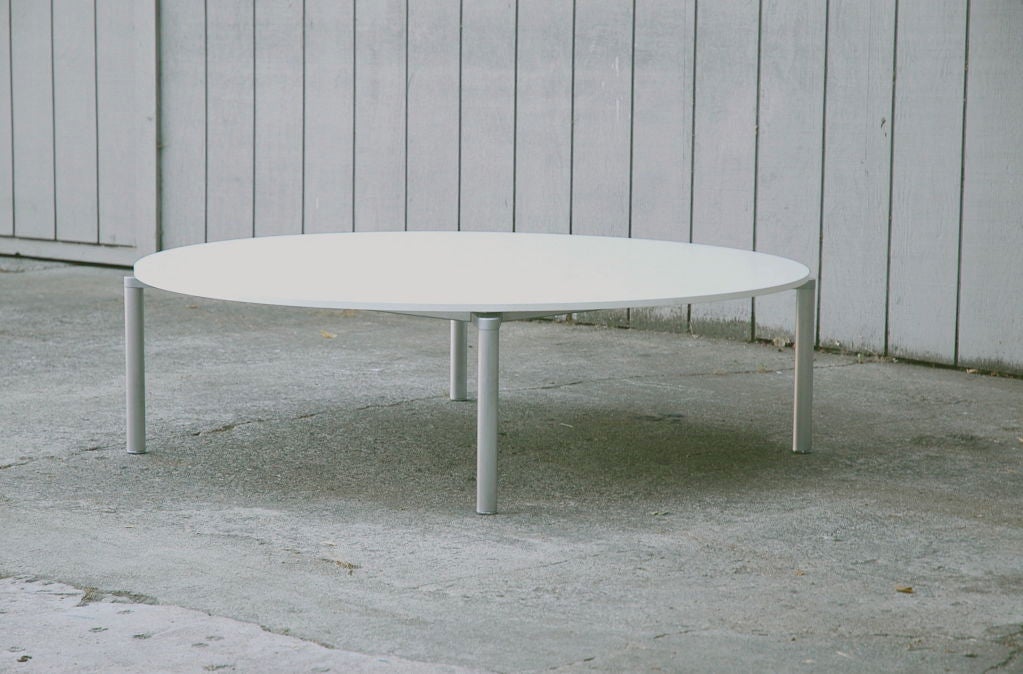 Large circular coffee table with white laminate top and floating metal legs.  Pelikan is a design partnership of Niels Gammelgaard and Lars Mathiesen where minimalism and high tech flair are seamlessly embodied in practical forms.