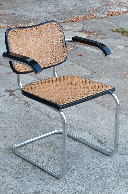 Comfortable 1928 classic Cesca chair by Marcel Breuer.  One of the first cantilevered chairs ever produced, shown here in bent tubular steel, with newly re-caned seat and piano black lacquer arms and seat.