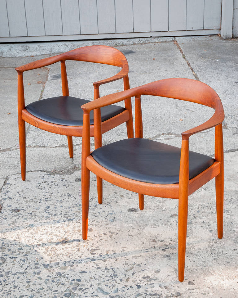 Pair of vintage teak armchairs with black leather seat.
Hans Wegner design for Johannes Hansen, 1949.
Classic form “The Chair,” or the “Round Chair.