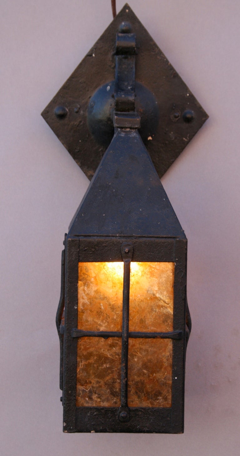 Circa 1920's wrought iron lantern with original amber mica mounting to wall with distinctive diamond-shaped backplate; completely rewired