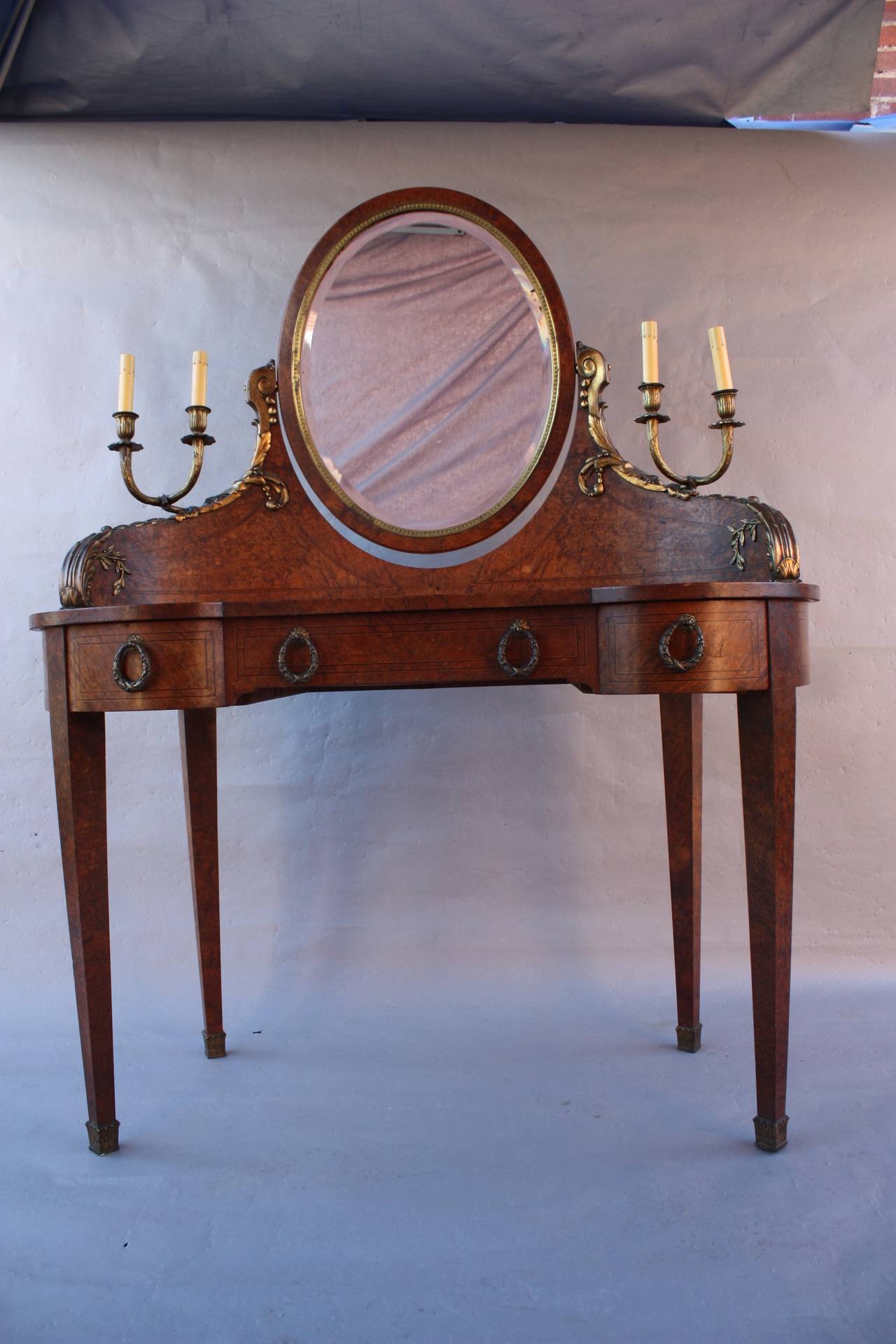 Vanity and mirror with beautiful burl wood and ormolu, circa 1910. The wood has a beautiful pattern and the two sconces were once electrified. Dimension: 45.5