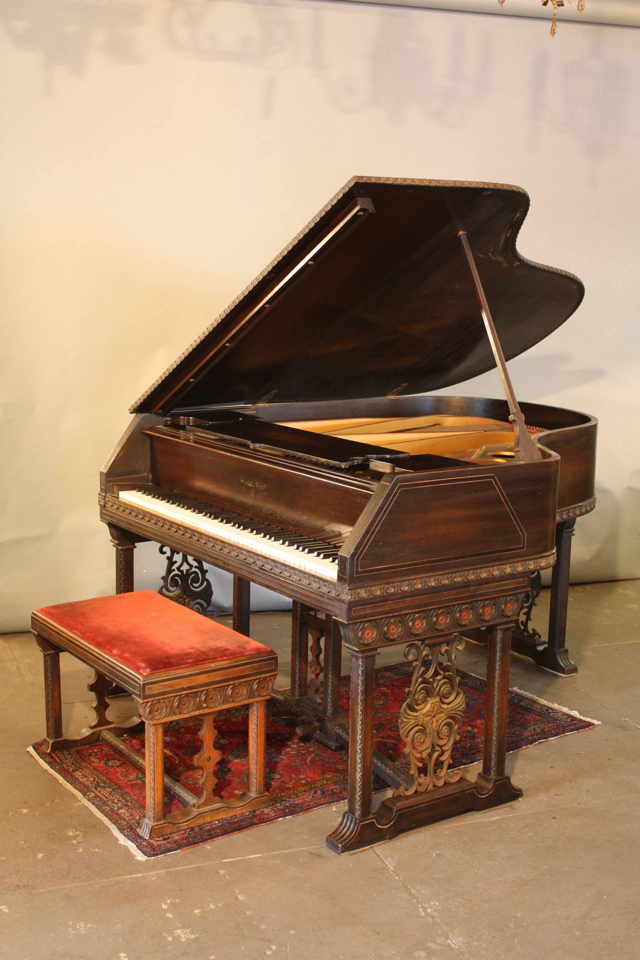 This amazing Spanish Revival style grand features an extraordinarily lovely case of English walnut, polychrome wood and iron details, circa 1920s. It retains its original finish, ivories, and matching bench, and plays beautifully. It measures