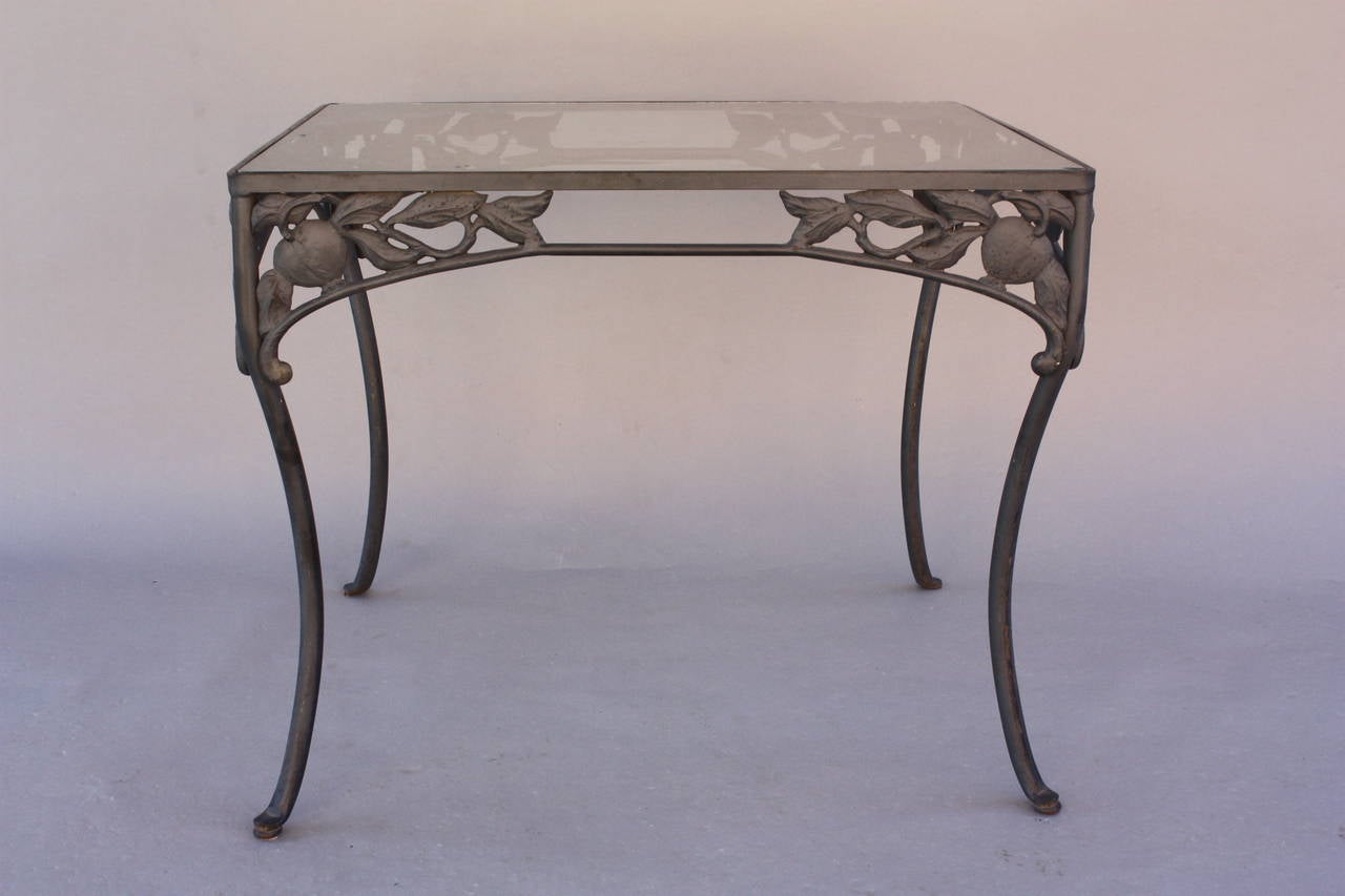 Wrought iron with cast aluminum pomegranate motif. The set is newly upholstered in exterior foam and Sunbrella fabric. Glass top.
Table measures 28 3/4