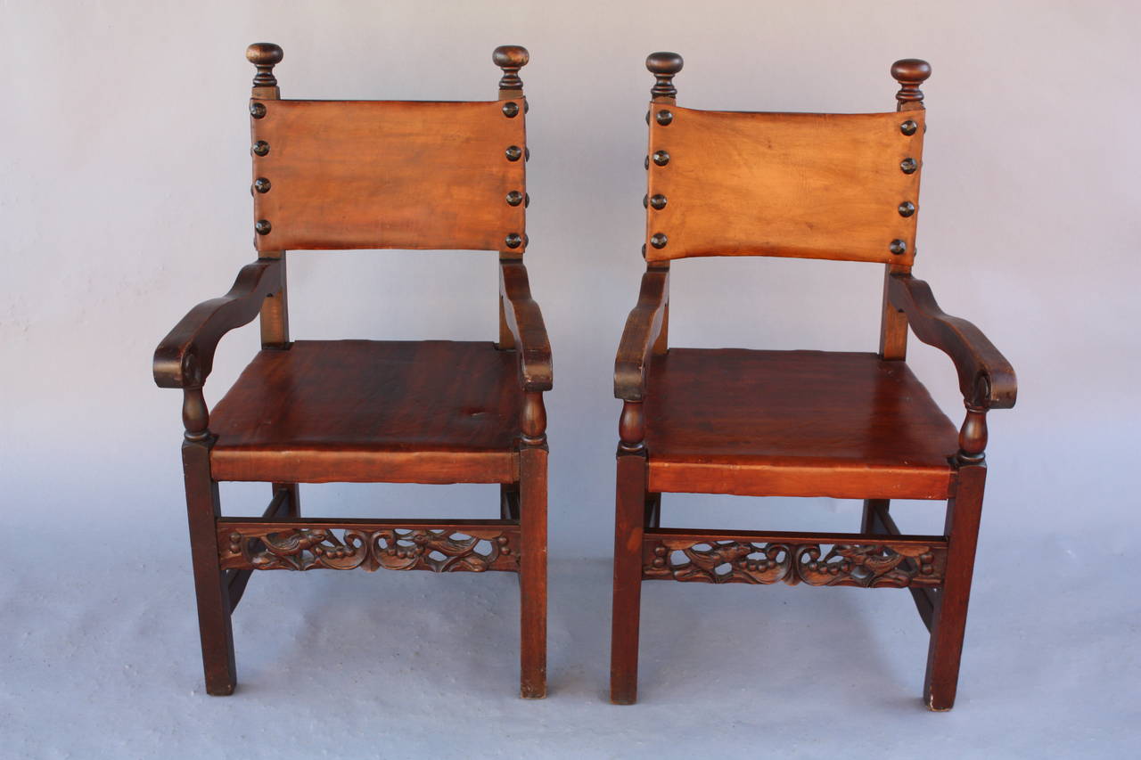 Circa 1920's armchairs with leather seats and carved bird motif stretchers. Measures 38 1/4