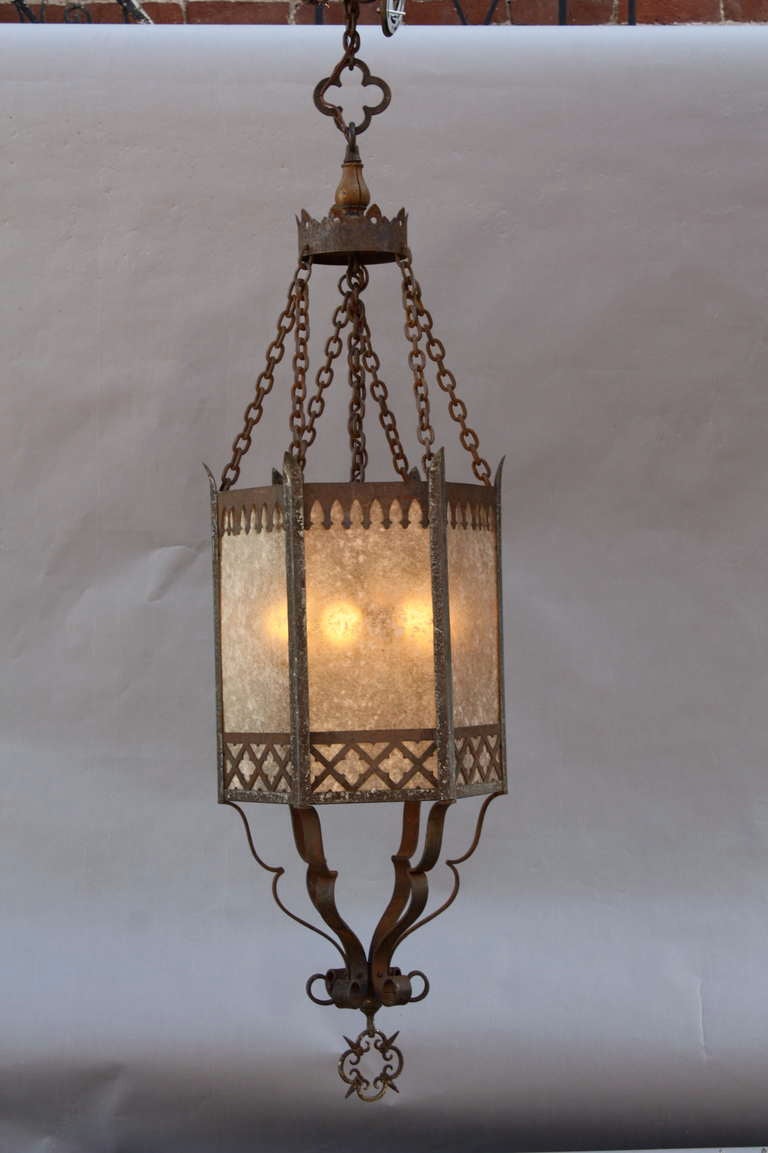 Nicely wrought large-scale lantern c. 1920's; perfect for an entry, alcove or above a staircase; decorative cutwork is silhouetted against the glow of new almond mica, and the fixture itself is suspended from multiple lengths of original chain. A
