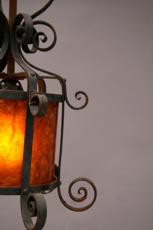 Charming wrought iron scrolled lantern lined in amber mica.  Would look great indoors or out.