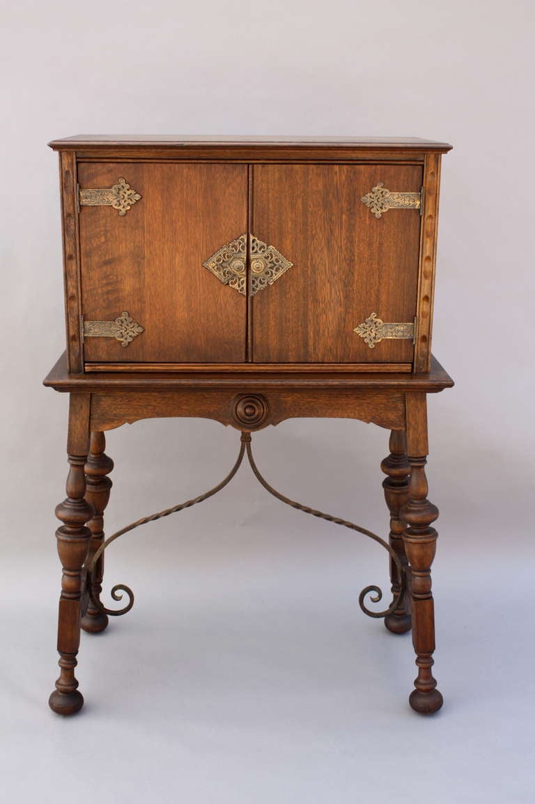 Handsome and functional writing desk concealed in vargueno-like cabinet, sits atop turned legs spanned by wrought iron stretcher; interior houses pull-out writing surface; measures approx. 31 3/4