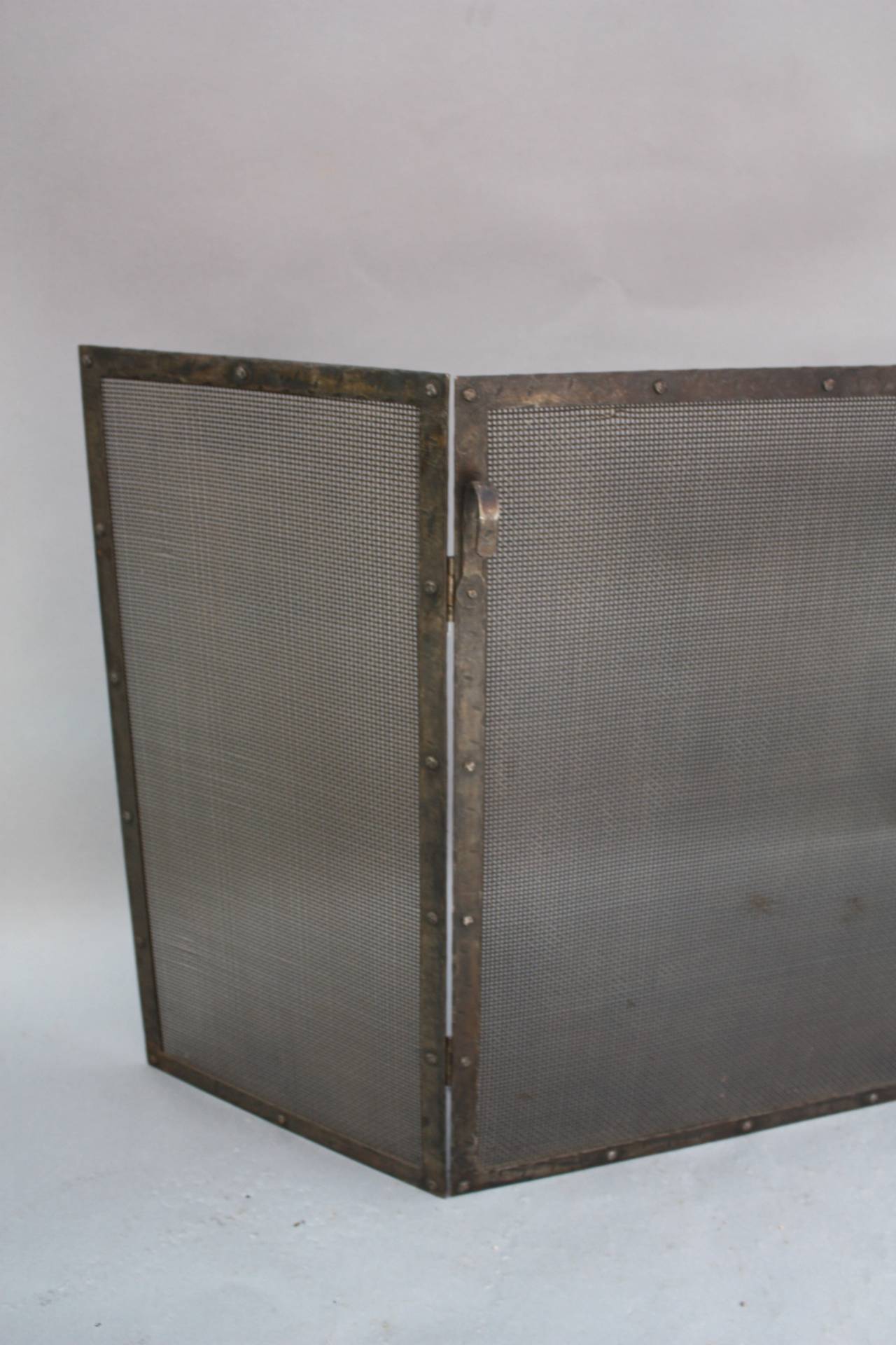 1920s wrought iron fire screen with riveted construction. The large panel measures 36 wide and the two side panels measure 15 wide. The height 30 1/4 tall.